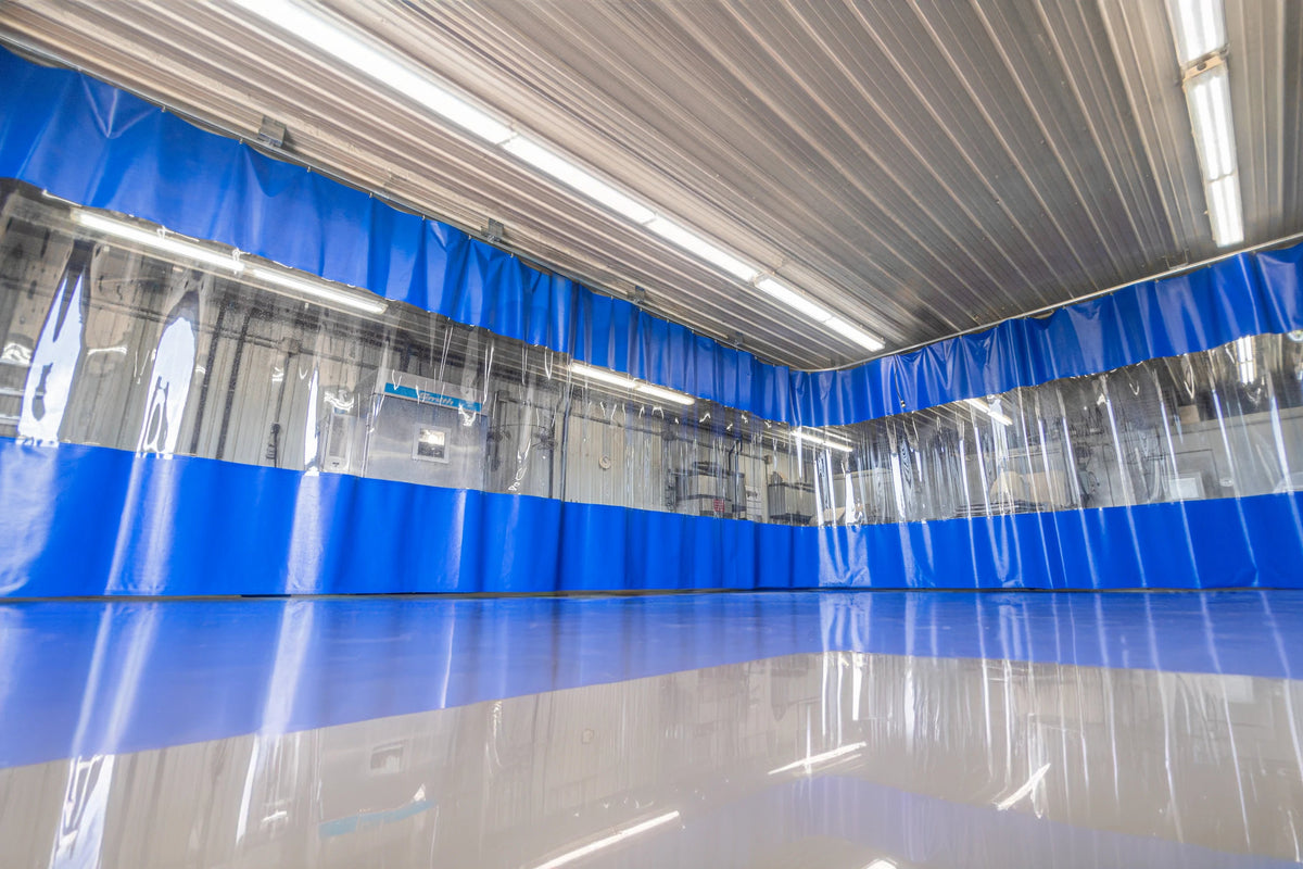A blue industrial curtain wall with a clear vision-panel band, enclosing a bay inside a warehouse